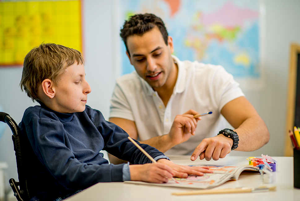 Special education teacher walking through a painting lesson with student.